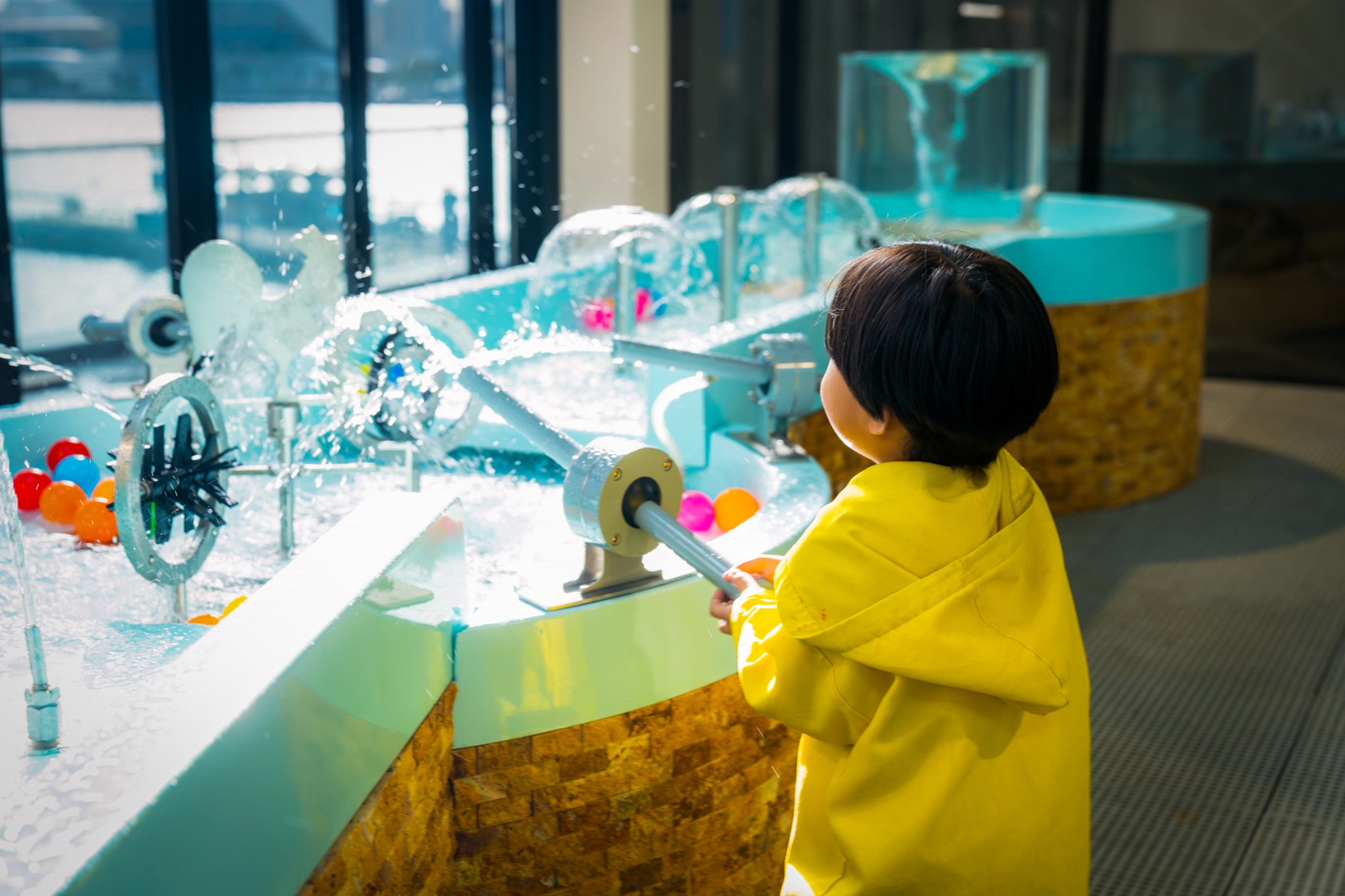 A child at a water play exhibit in the woo-hoo! children's museum, X Distrikt